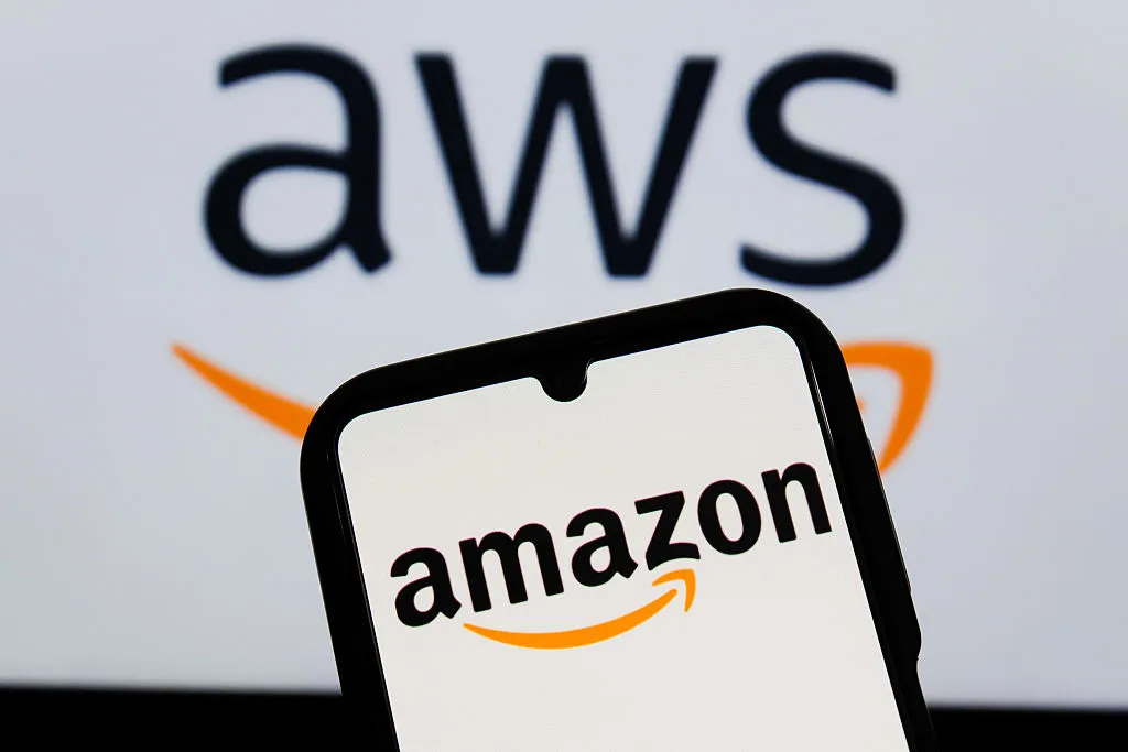 Smartphone screen displaying the Amazon logo with a blurred AWS logo in the background
