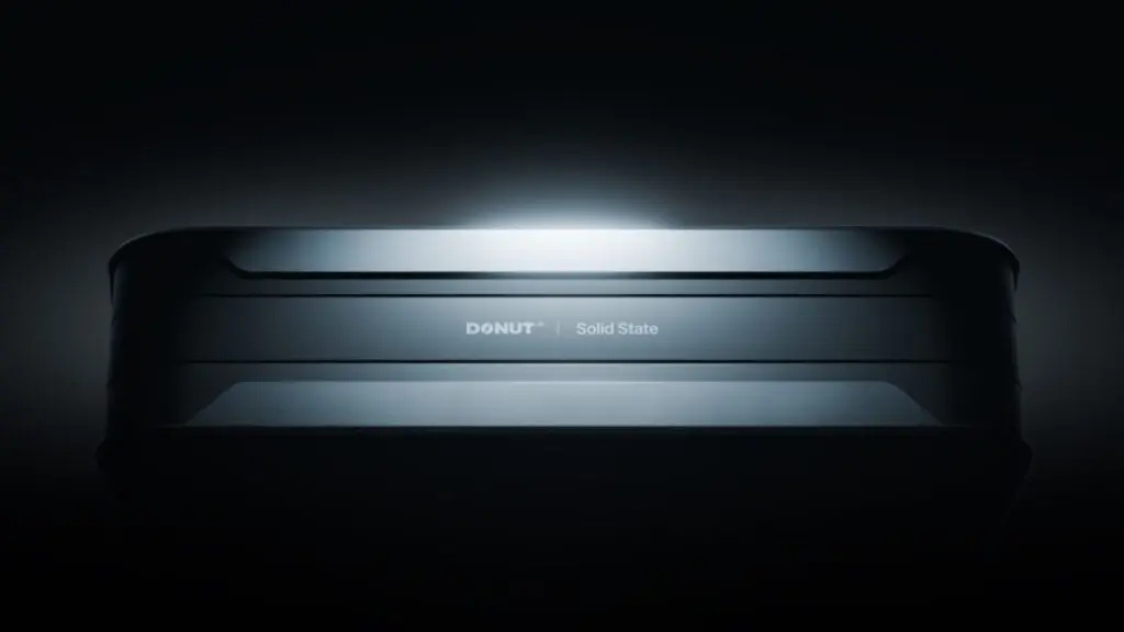 Dark cinematic reveal of a solid-state battery prototype on stage at CES 2026 with subtle backlighting highlighting next-generation energy technology
